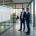 Zwei Berater prüfen im Glasbüro die ILM-Objektliste aus SAP-Hinweis 2122906 vor einem Bildschirm mit Unternehmenssoftware (KI-generiertes Bild)